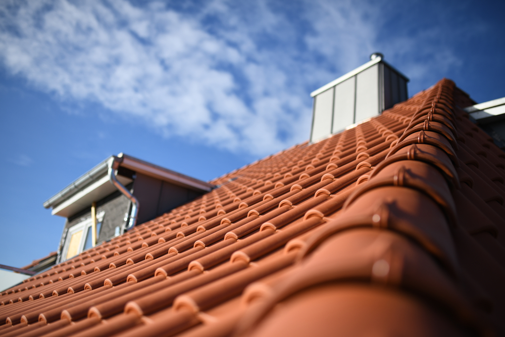 Roofer,Shows,Red,Clay,Material,Tiles,On,Residential,Building,,Roofers